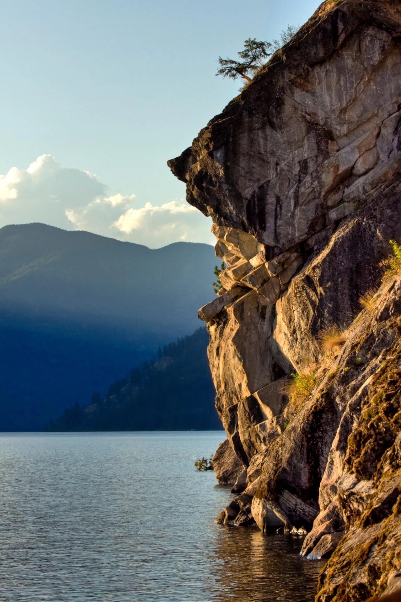 Sunlit cliff rising from a mountain lake
